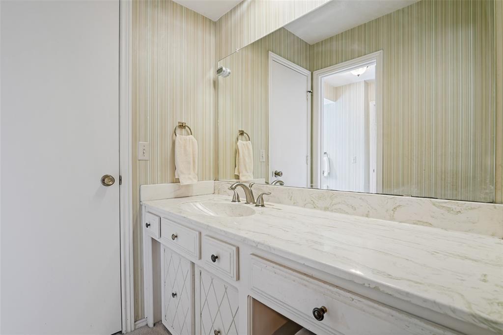Vanity with an integrated sink, brushed nickel faucet, light-toned countertop, and white cabinetry with dark hardware