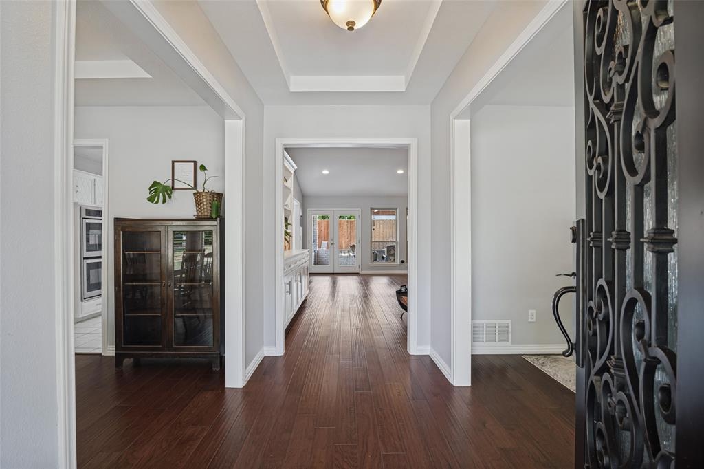 Entryway with dark wood-finish flooring, white trim, and a tray ceiling