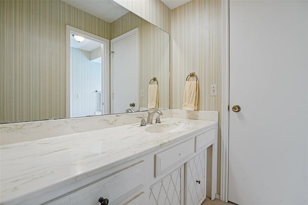 Vanity featuring a stone-finish countertop, integrated sink, and dual-handle faucet