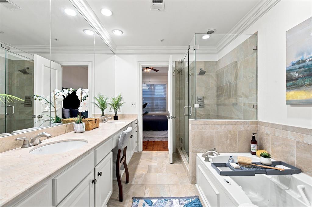 Double vanity with undermount sinks, recessed lighting, glass-enclosed shower, and built-in soaking tub