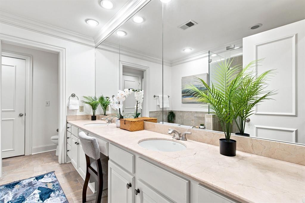 Dual vanity with integrated sinks, light stone countertop, and ample storage cabinetry