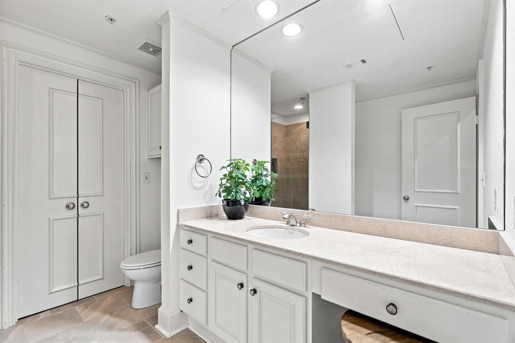 Dual-sink vanity with light-toned countertop, built-in cabinetry, and tile flooring