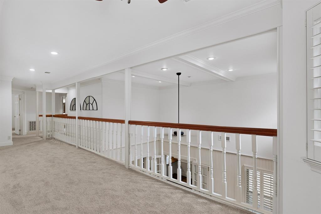 Carpeted hallway with white railing and wood-finish top rail, recessed lighting, and crown molding