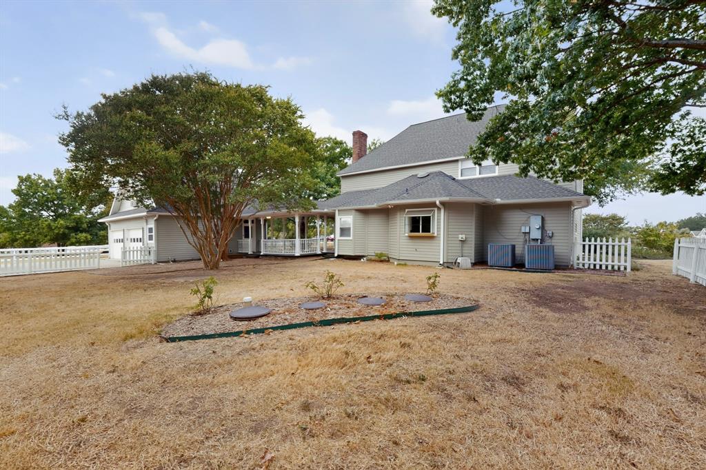 Two-story residence with light-colored siding, a covered porch, an attached two-car garage, and a picket fence