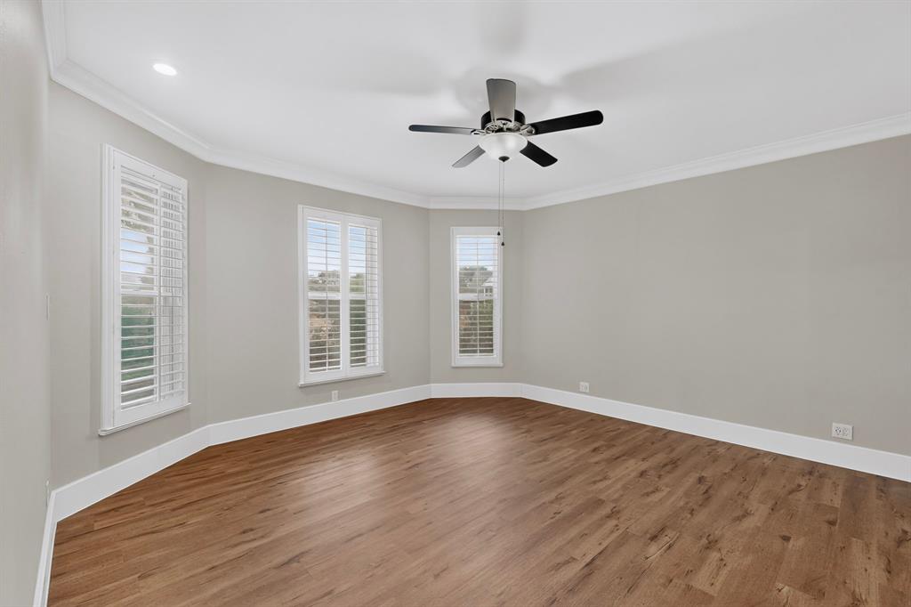 Wood-finish flooring throughout, multiple windows with plantation shutters, recessed ceiling lighting, crown molding, and a ceiling fan with light fixture