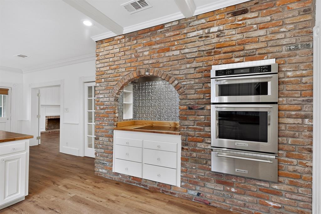 Exposed brick wall with an arched niche featuring a tin tile backsplash
