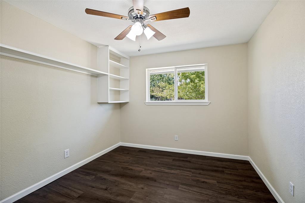Wood-finish flooring, built-in shelving, white trim, recessed window, and a ceiling fan with integrated lighting