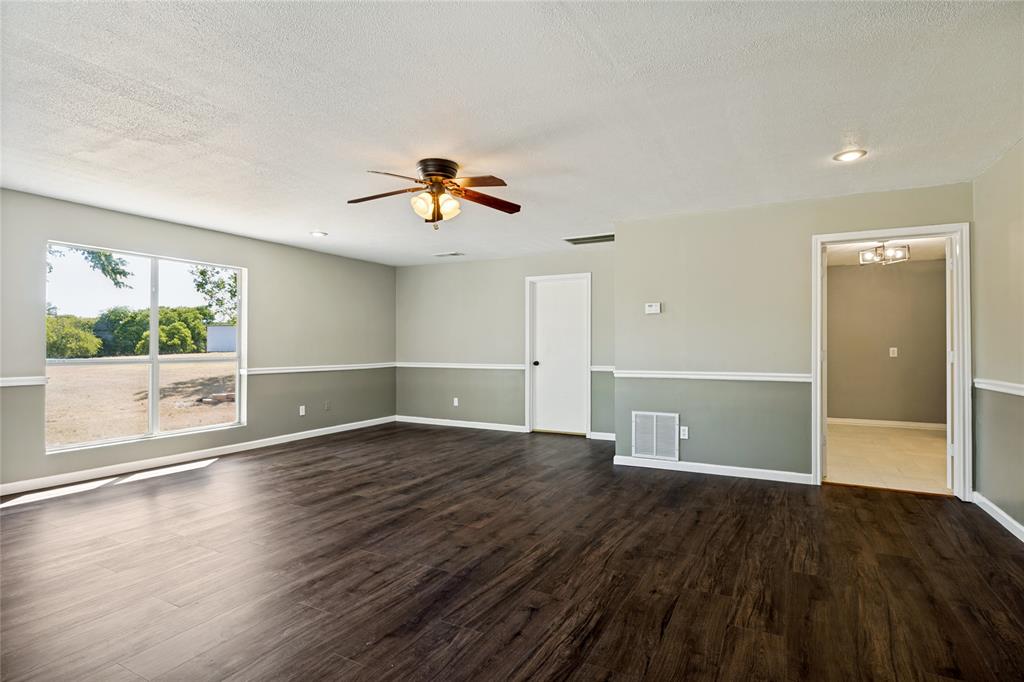 Spacious room featuring wood-finish flooring, a ceiling fan with integrated lighting, recessed lighting, and a large picture window