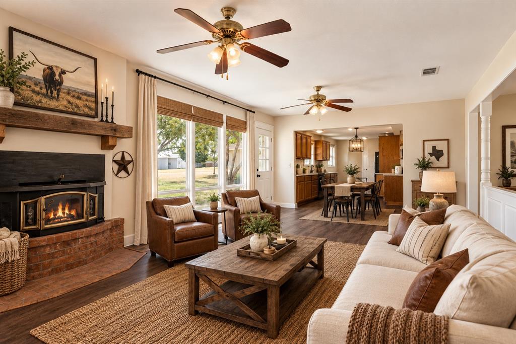 Brick fireplace with a dark mantel, wood-finish flooring, and a ceiling fan