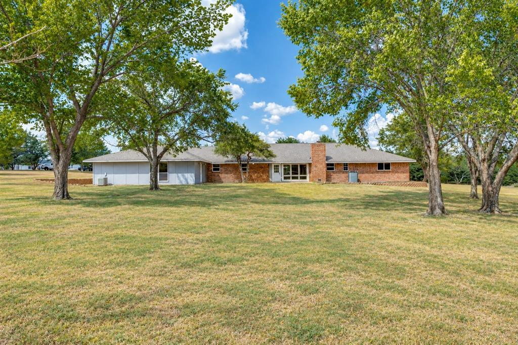 Expansive green space featuring mature trees and a brick and siding exterior