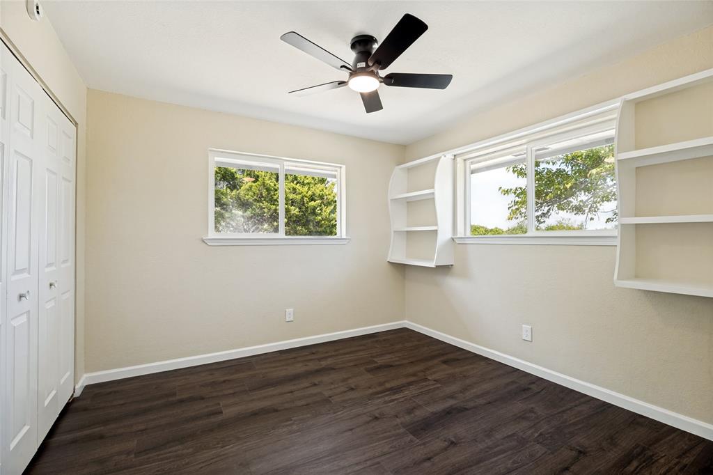 Wood-finish flooring, two large windows, built-in shelving, ceiling fan with light, and bi-fold closet doors