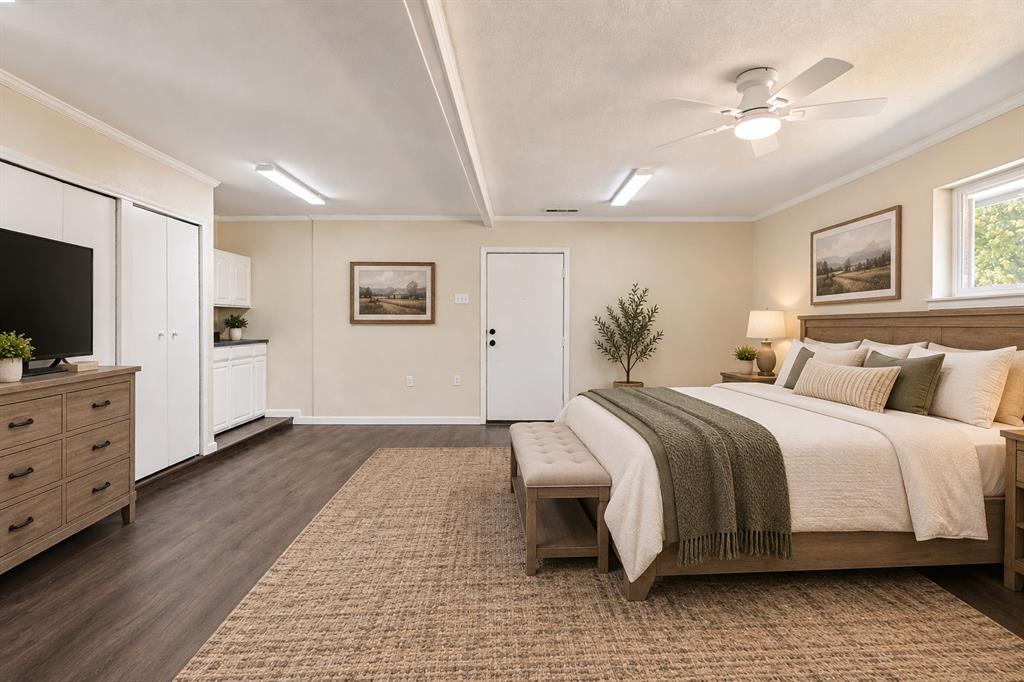 Wood-finish flooring with a ceiling fan, a window, and built-in white cabinetry