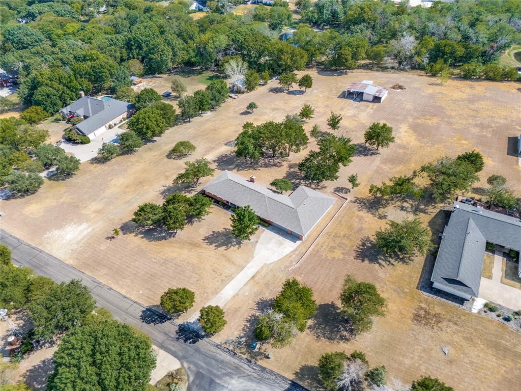Expansive property featuring a single-story residence, a lengthy paved driveway, and mature landscaping