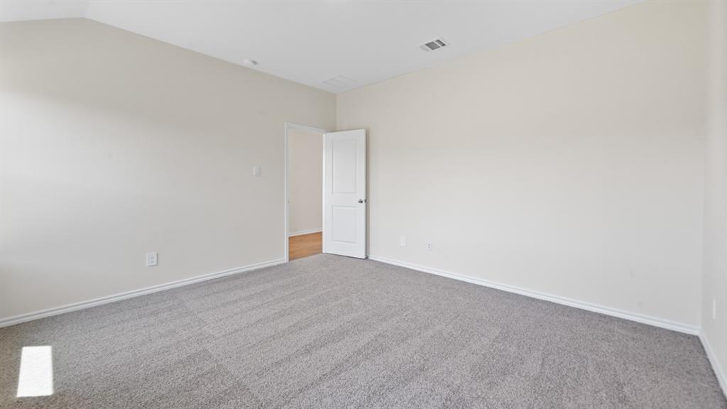 Spacious room featuring light neutral wall paint, gray carpeting, and white baseboards