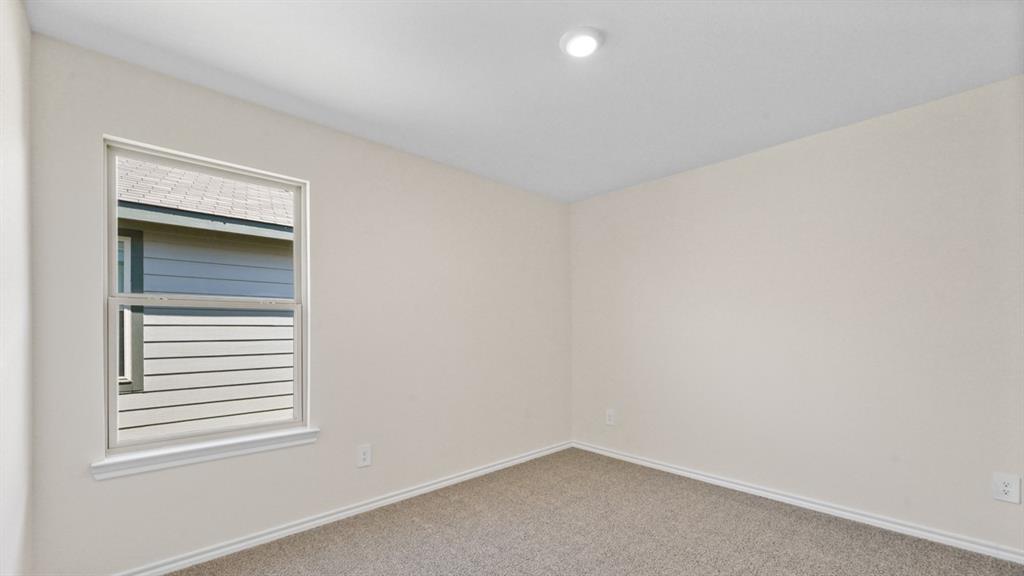 Neutral wall paint, carpet flooring, a window with white trim, and a recessed ceiling light fixture