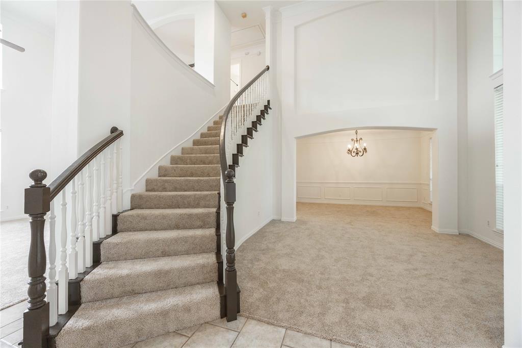 Curved staircase with wood newel posts and balusters, carpeted treads, and tiled entry Curved staircase with wood newel posts and balusters, carpeted treads, and tiled entry