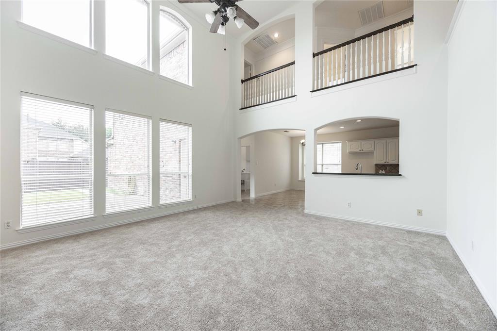Two-story living area with high ceilings, upper-level windows, and an arched pass-through to the kitchen