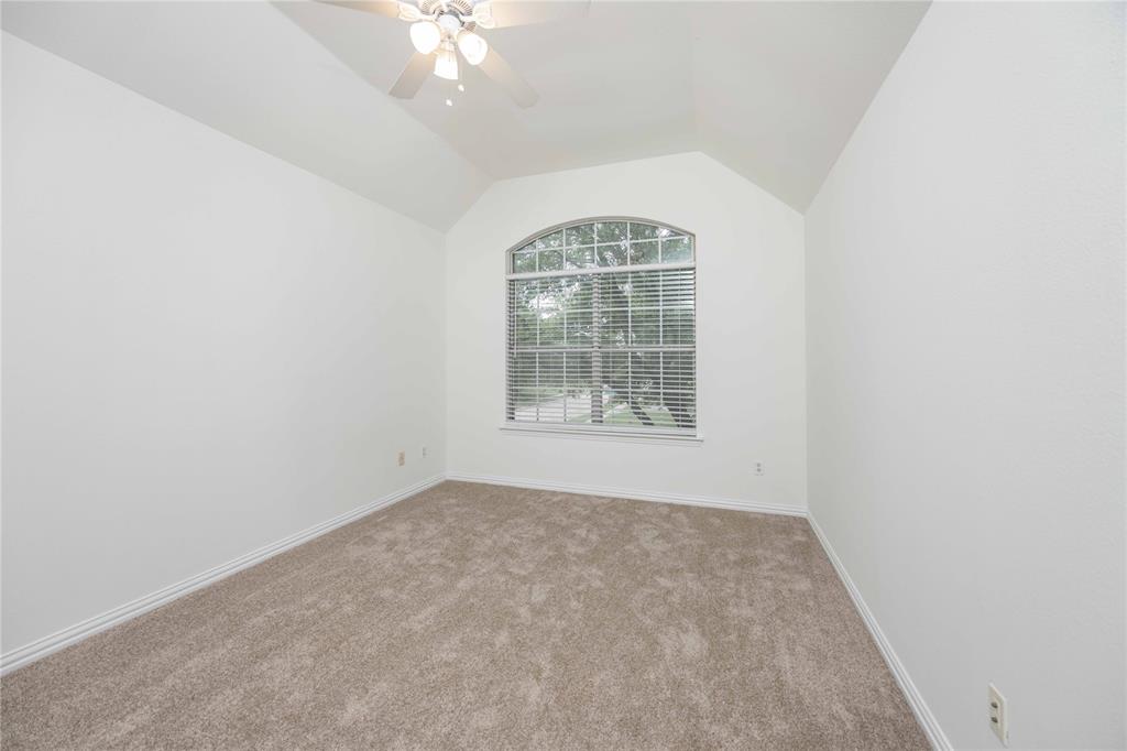Vaulted ceiling with an installed ceiling fan, an arched window, and carpet flooring
