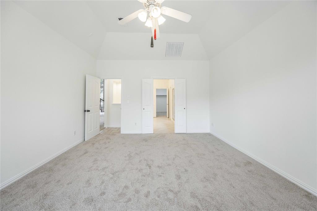 Vaulted ceiling, light-toned carpet, white walls, ceiling fan with light fixture, and white interior doors