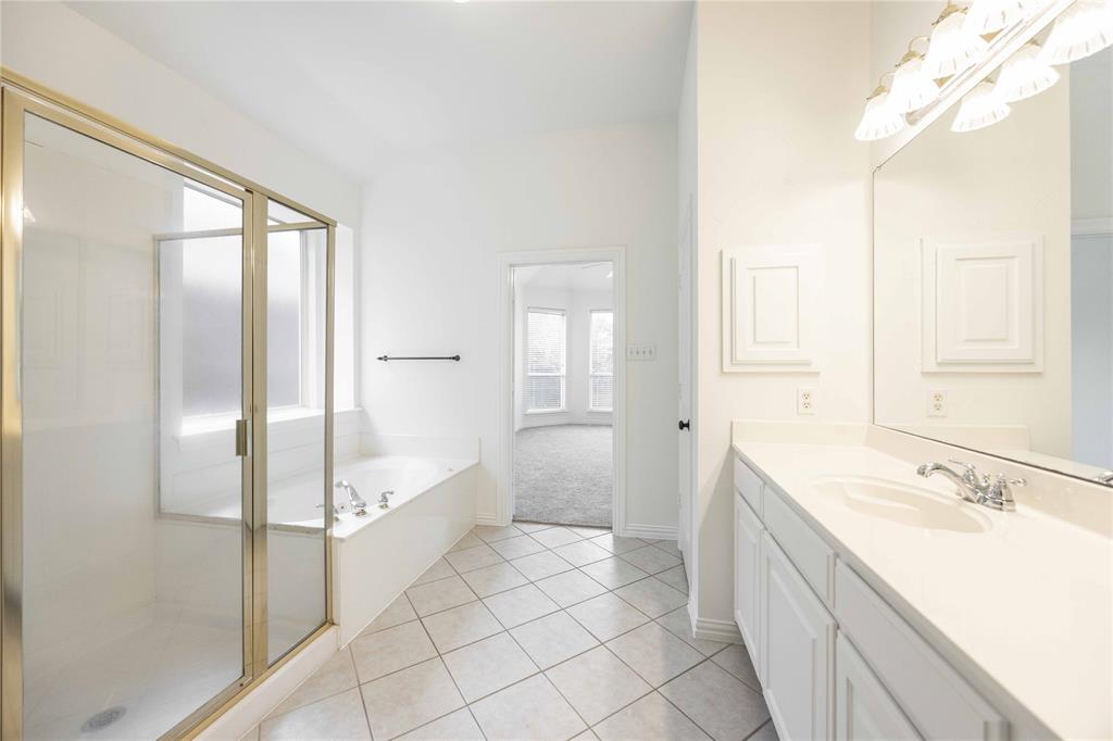 White tiled flooring, vanity with a single basin, built-in storage above the vanity, separate shower, and built-in bathtub