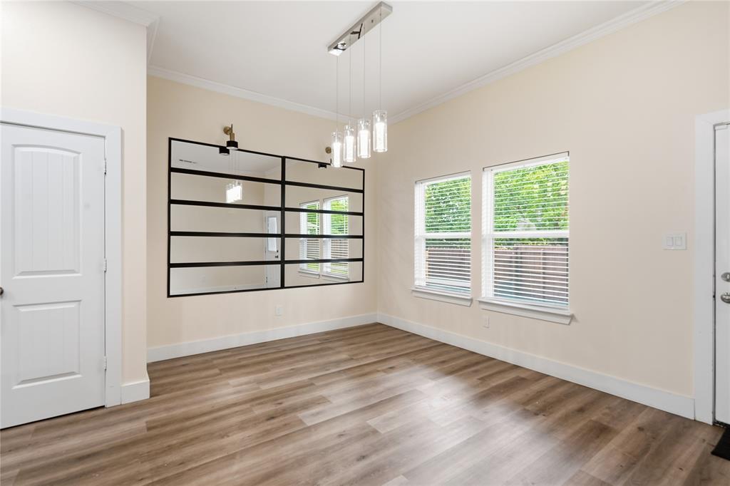 Bright and elegant dining area featuring abundant natural light, soaring ceilings, luxury vinyl plank flooring, a custom oversized statement mirror with lights and designer pendant lighting