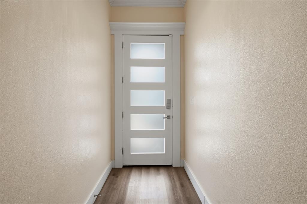 Modern entryway featuring a contemporary front door with frosted glass panels, soaring ceilings, elegant crown molding, and luxury vinyl plank flooring that creates a bright and welcoming first impression