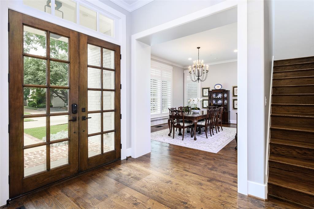 Wood-finish flooring throughout the entry, double front doors with transom, and a dedicated dining space featuring a chandelier and window shutters Wood-finish flooring throughout the entry, double front doors with transom, and a dedicated dining space featuring a chandelier and window shutters