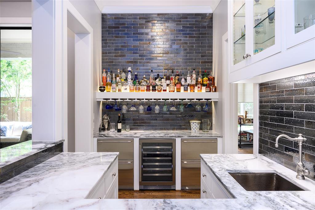 Wet bar with integrated wine refrigerator, under-cabinet lighting, glass-front cabinetry, and a subway tile backsplash Wet bar with integrated wine refrigerator, under-cabinet lighting, glass-front cabinetry, and a subway tile backsplash
