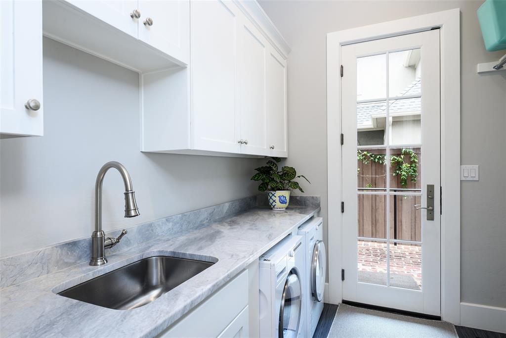 White cabinetry, undermount sink, stone countertop, brushed nickel faucet, and a glass-paned door