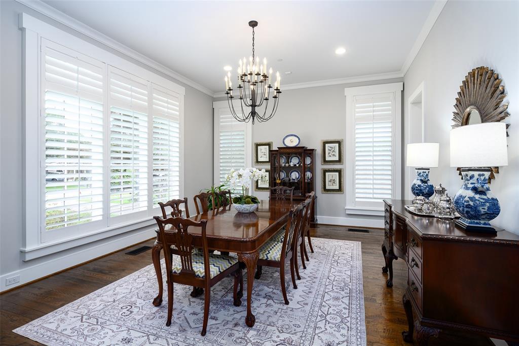 Hardwood flooring, crown molding, white plantation shutters, built-in cabinetry, and a chandelier Hardwood flooring, crown molding, white plantation shutters, built-in cabinetry, and a chandelier