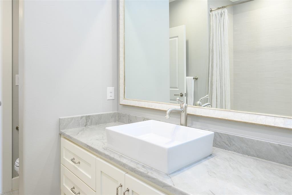 Vanity with a rectangular vessel sink, polished chrome faucet, stone countertop, and custom cabinetry