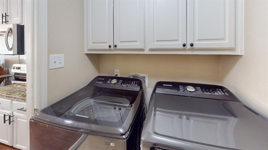 Laundry area with built-in white cabinetry and black hardware