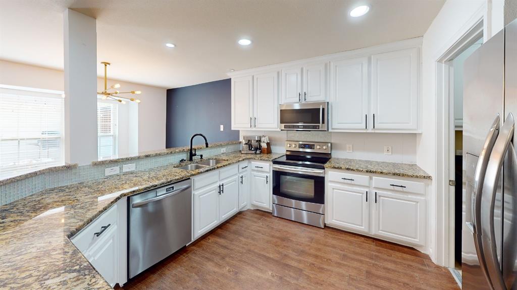 Kitchen featuring white cabinetry, stainless steel appliances, granite countertops, and wood-finish flooring