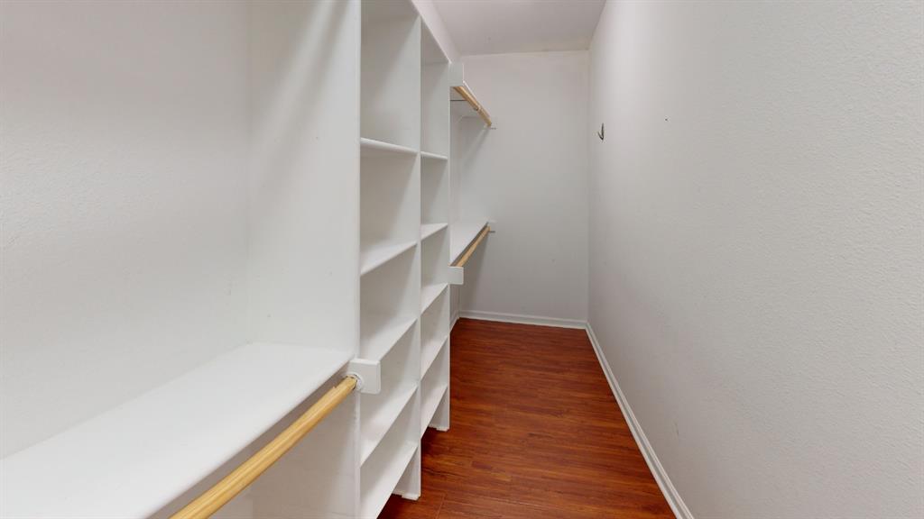 Walk-in closet with extensive built-in shelving, hanging rods, and wood-finish flooring