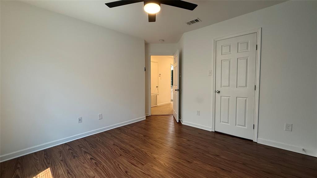 Wood-finish flooring, white paneled door, and a ceiling fan with integrated lighting