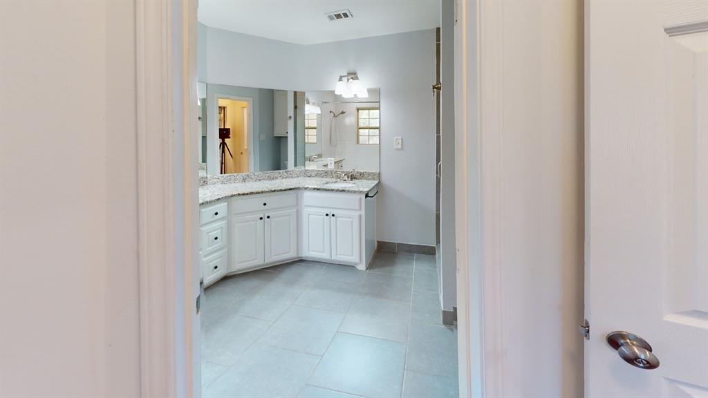 Dual vanity with white cabinetry, granite-style countertop, and expansive wall-mounted mirror