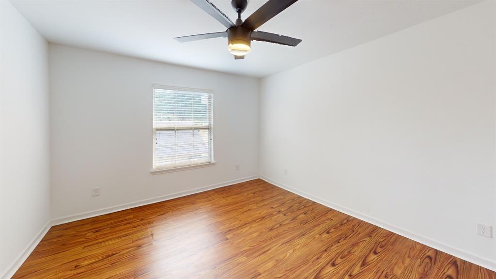 Hardwood-finish flooring, white walls, single window with blinds, and a ceiling fan with integrated lighting