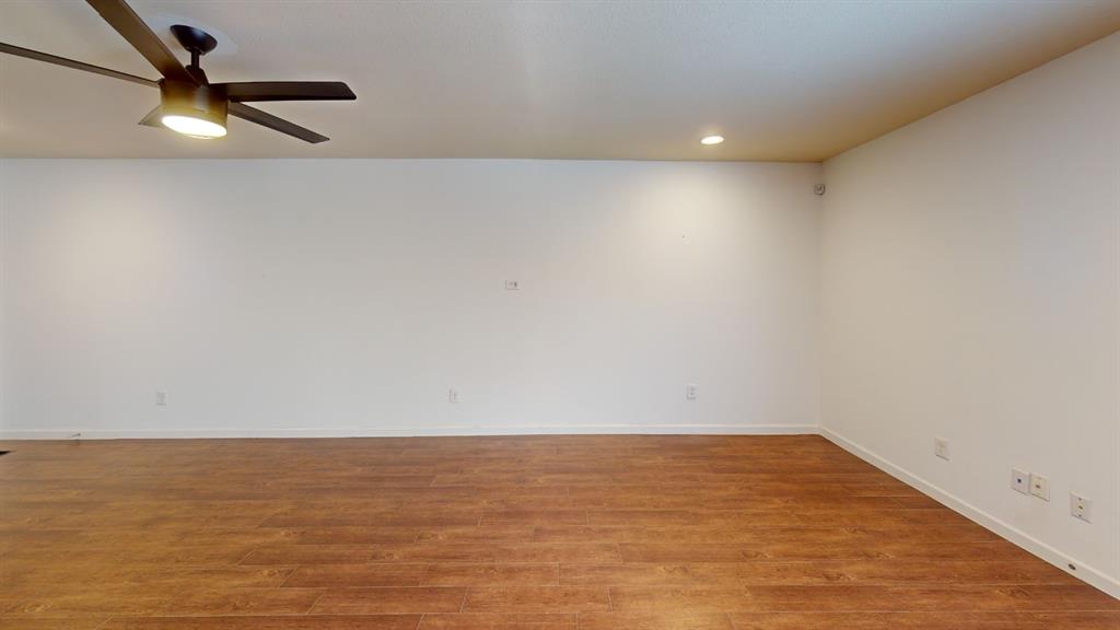Wood-finish flooring with white baseboards, recessed ceiling lighting, and a ceiling fan with integrated light
