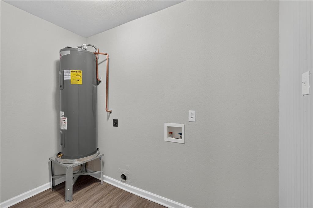 Dedicated utility space with a water heater, laundry hookups, and wood-finish flooring