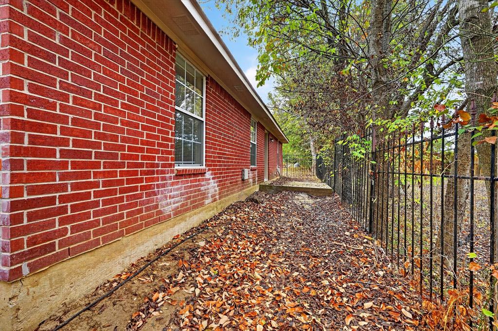 Red brick exterior with white window trim and a black metal fence
