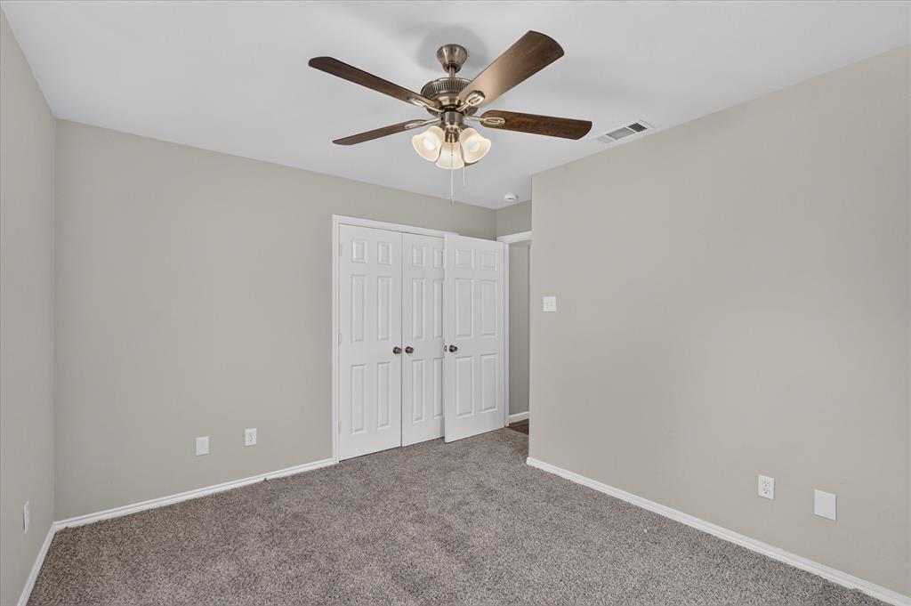 Neutral wall color, carpeted flooring, bi-fold closet doors, and a ceiling fan with integrated lighting