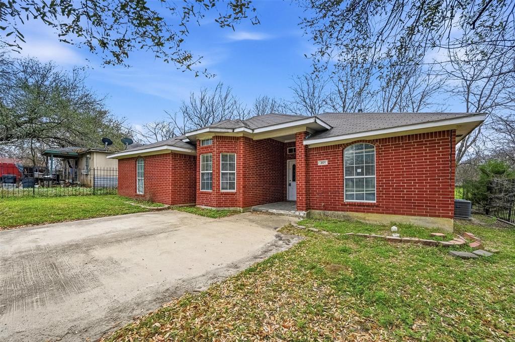 Red brick exterior with a multi-paned bay window, arched window, and a concrete driveway