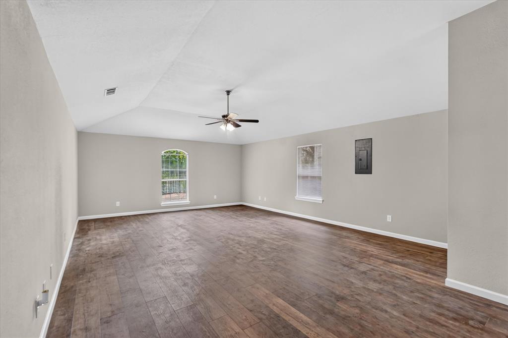 Vaulted ceiling, wood-finish flooring, ceiling fan, arched window, and neutral wall tones