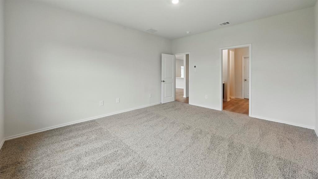 Spacious room featuring neutral carpeting, white baseboards, light-toned wall paint, and recessed lighting