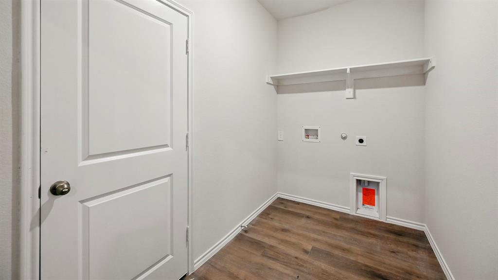 Utility room featuring wood-finish flooring, white walls, and a built-in shelving unit