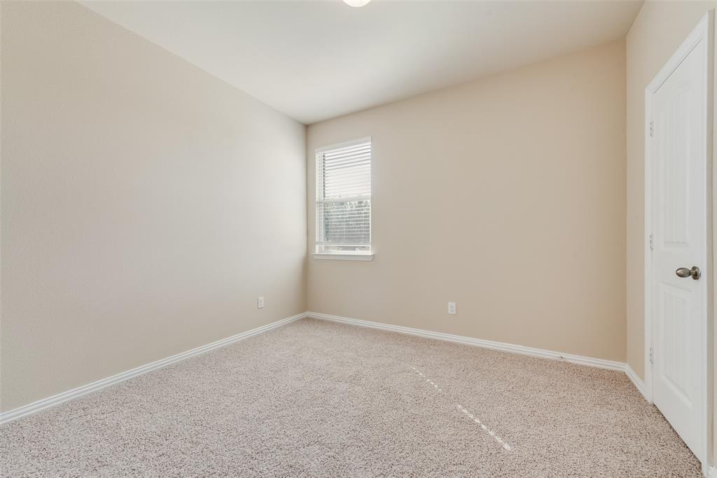 Neutral-toned walls, textured carpet flooring, a single window with blinds, and a white paneled door with a metallic knob