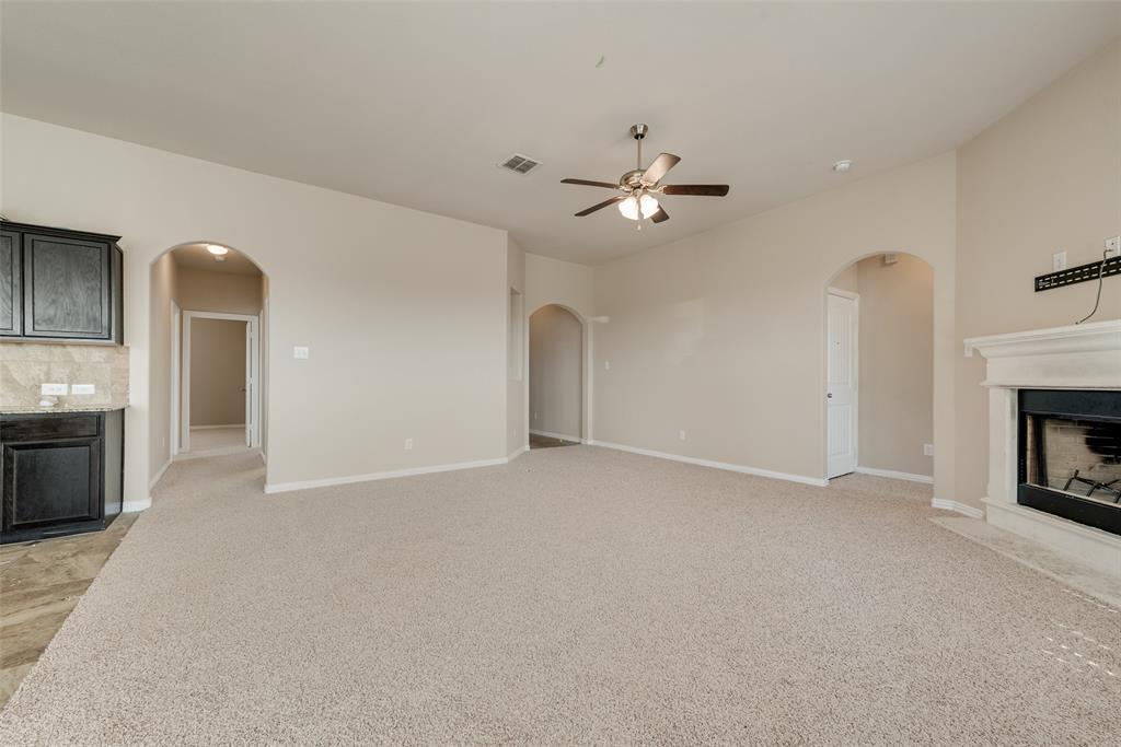 Recessed fireplace with a white mantel, ceiling fan with light fixture, arched doorways, and light-toned carpeting Recessed fireplace with a white mantel, ceiling fan with light fixture, arched doorways, and light-toned carpeting