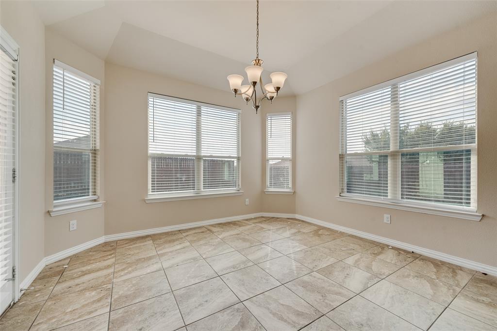 Recessed ceiling with a chandelier, bay windows with blinds, and square tile flooring