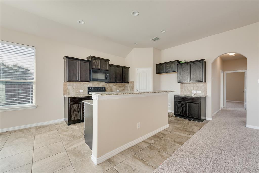 Kitchen area featuring dark wood-finish cabinetry, light-toned tiled flooring, recessed lighting, and a breakfast bar