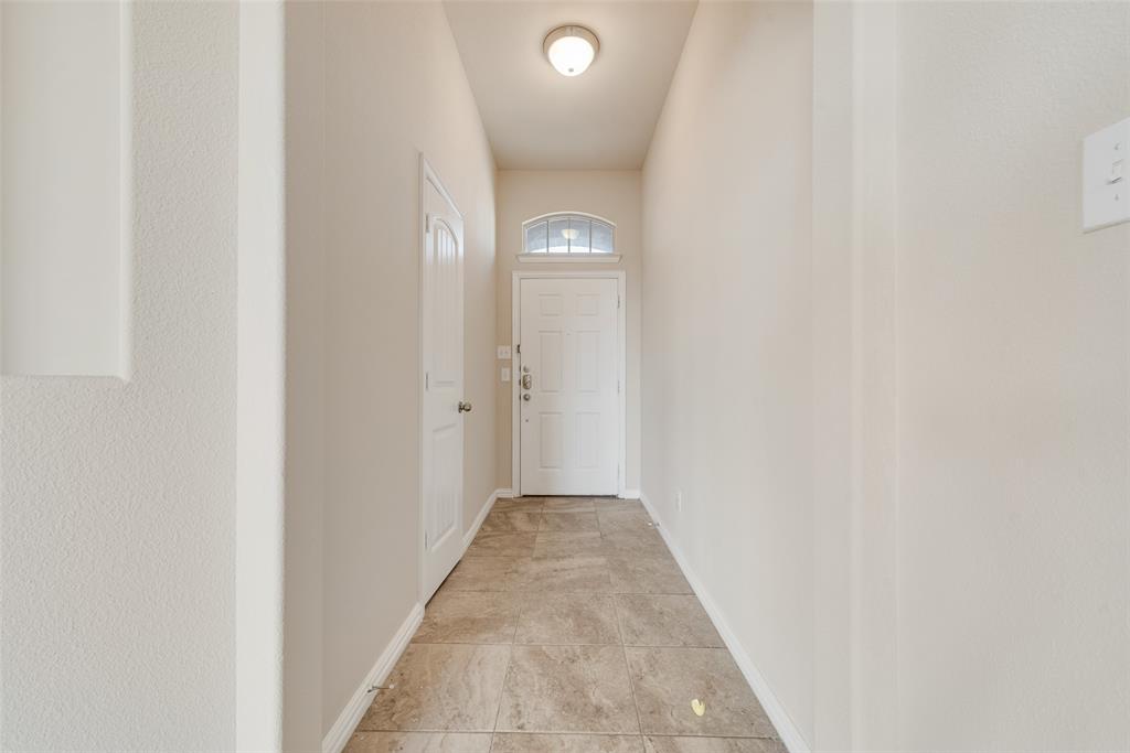 Foyer featuring ceramic tile flooring, a white paneled door with an arched transom, and a flush-mount ceiling light fixture Foyer featuring ceramic tile flooring, a white paneled door with an arched transom, and a flush-mount ceiling light fixture